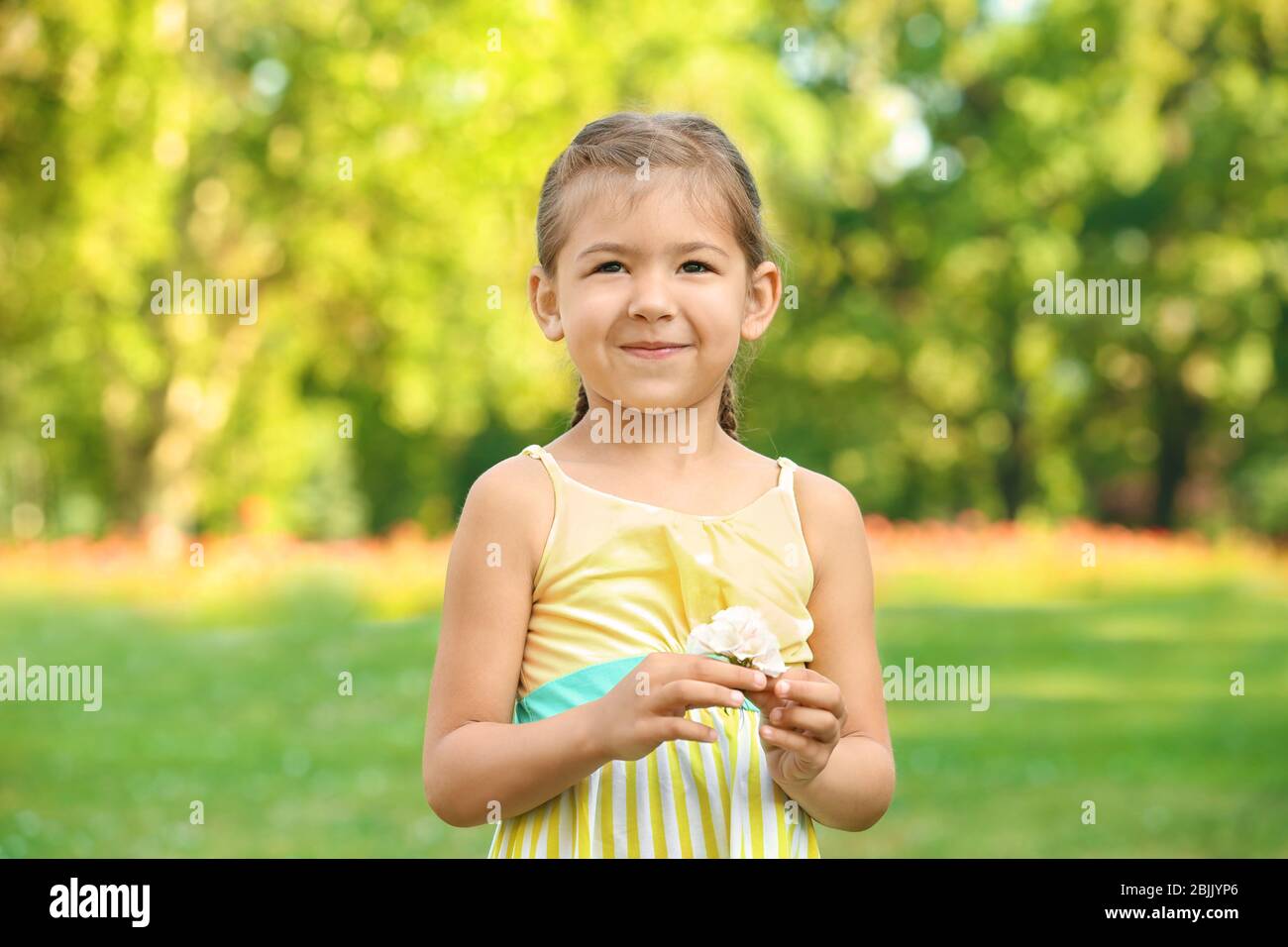 Cute little girl with flowers outdoors Stock Photo - Alamy