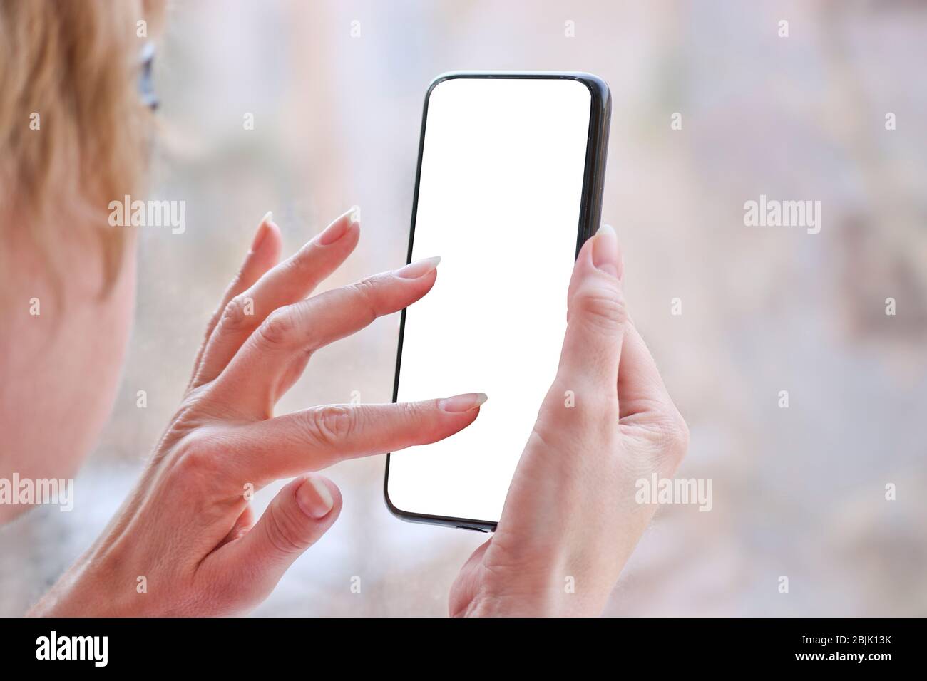 Female hand with smartphone, white blank screen with copy space. Stock Photo