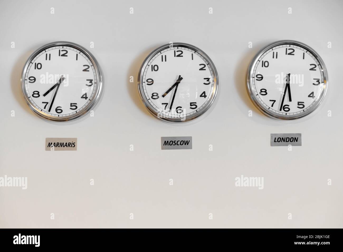 Clocks showing time in different cities on wall in hotel Stock Photo
