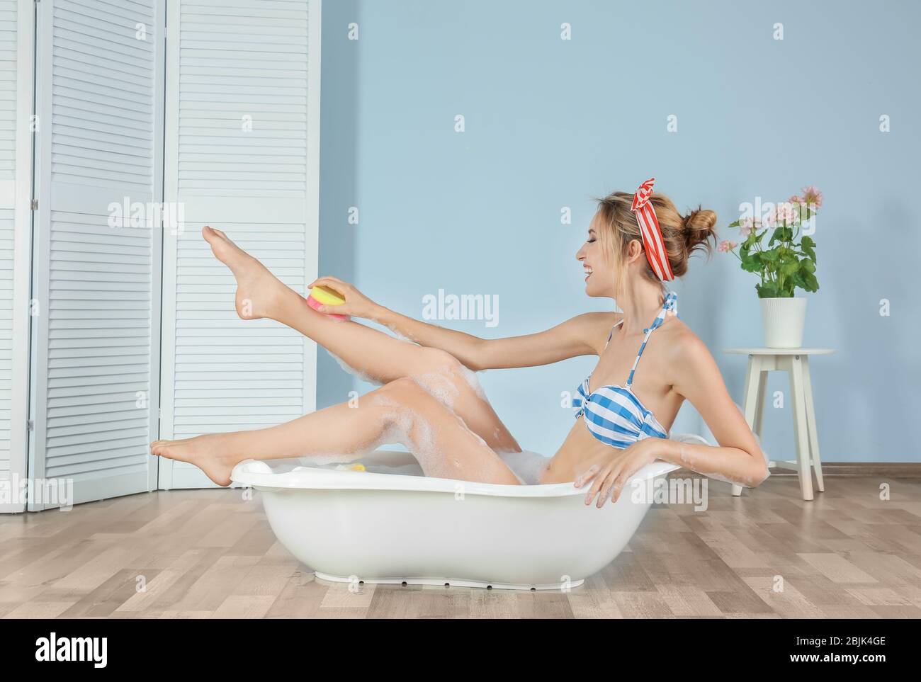 Funny young woman in bikini taking bath at home Stock Photo