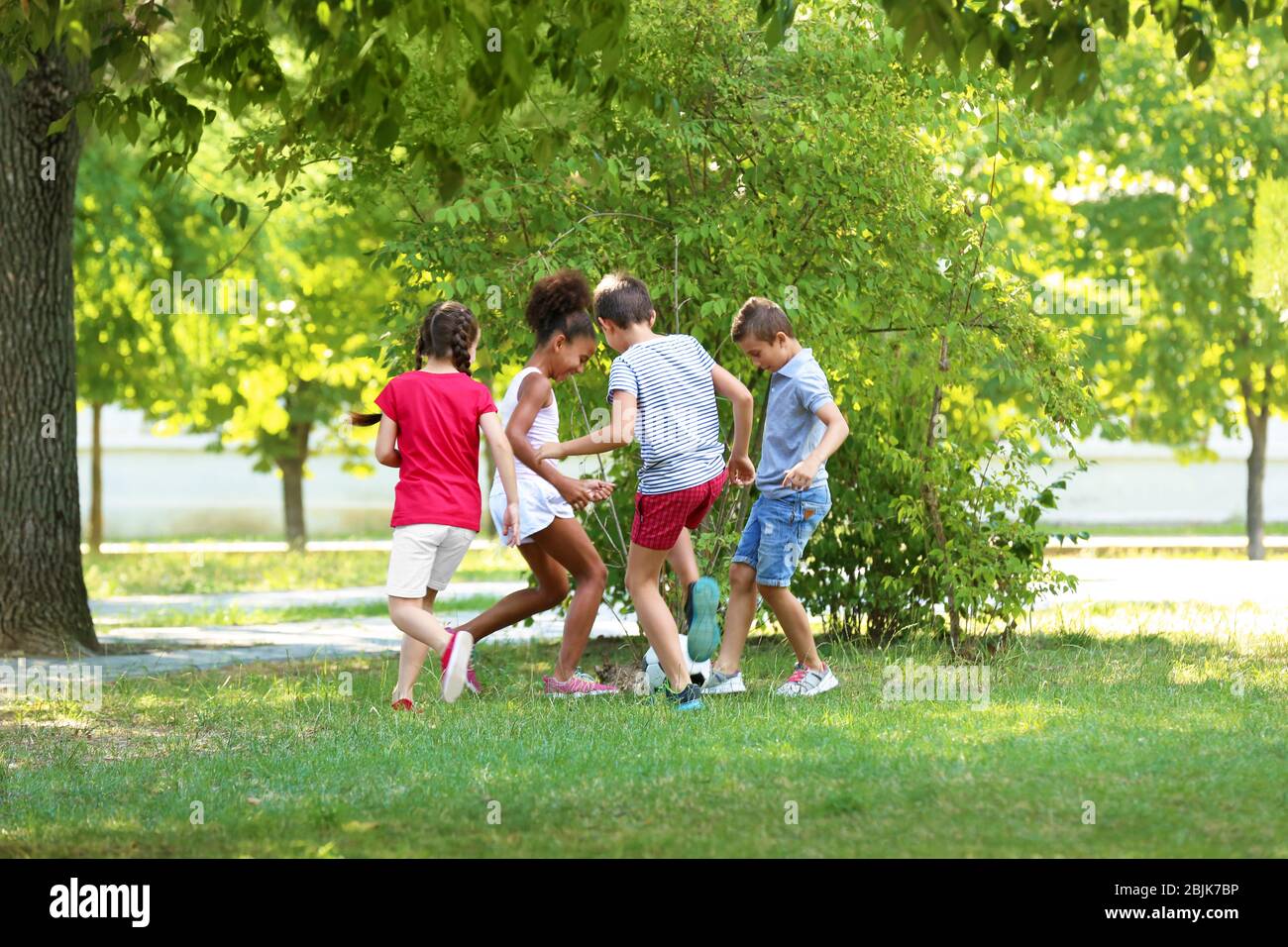 Cute children playing football in park Stock Photo - Alamy