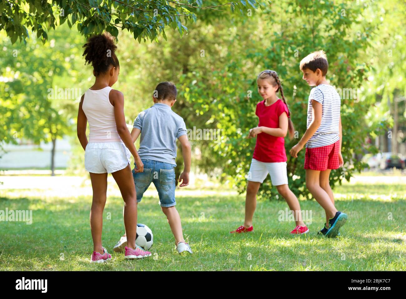 Cute children playing football in park Stock Photo - Alamy