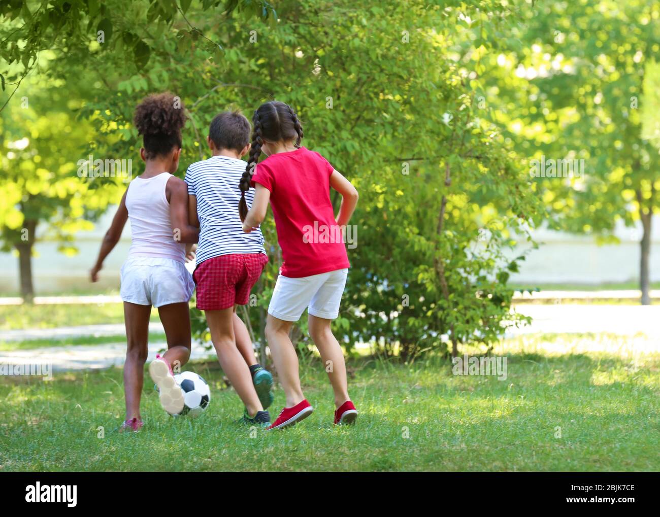 Cute children playing football in park Stock Photo - Alamy
