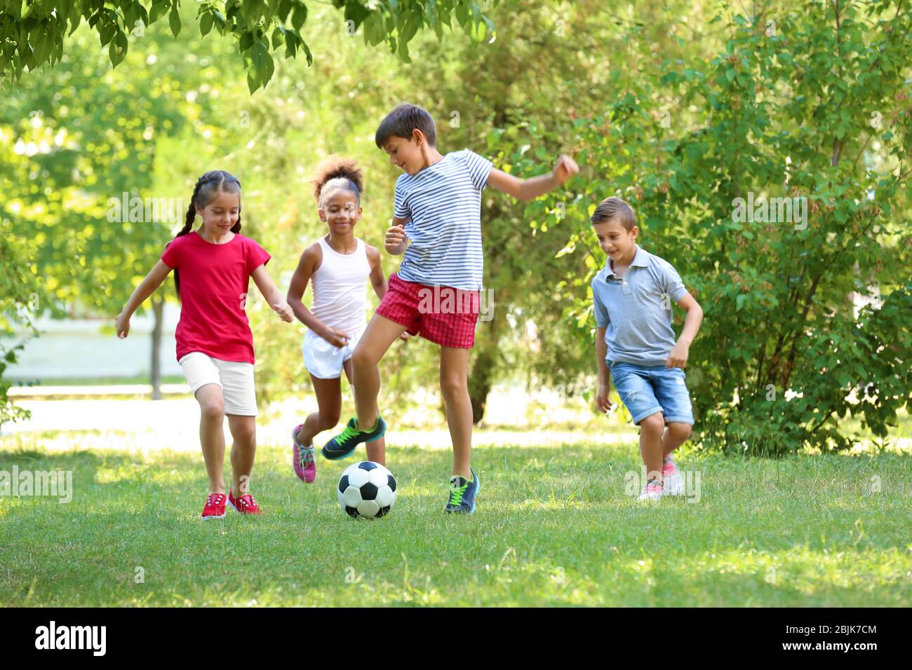 Cute children playing football in park Stock Photo - Alamy