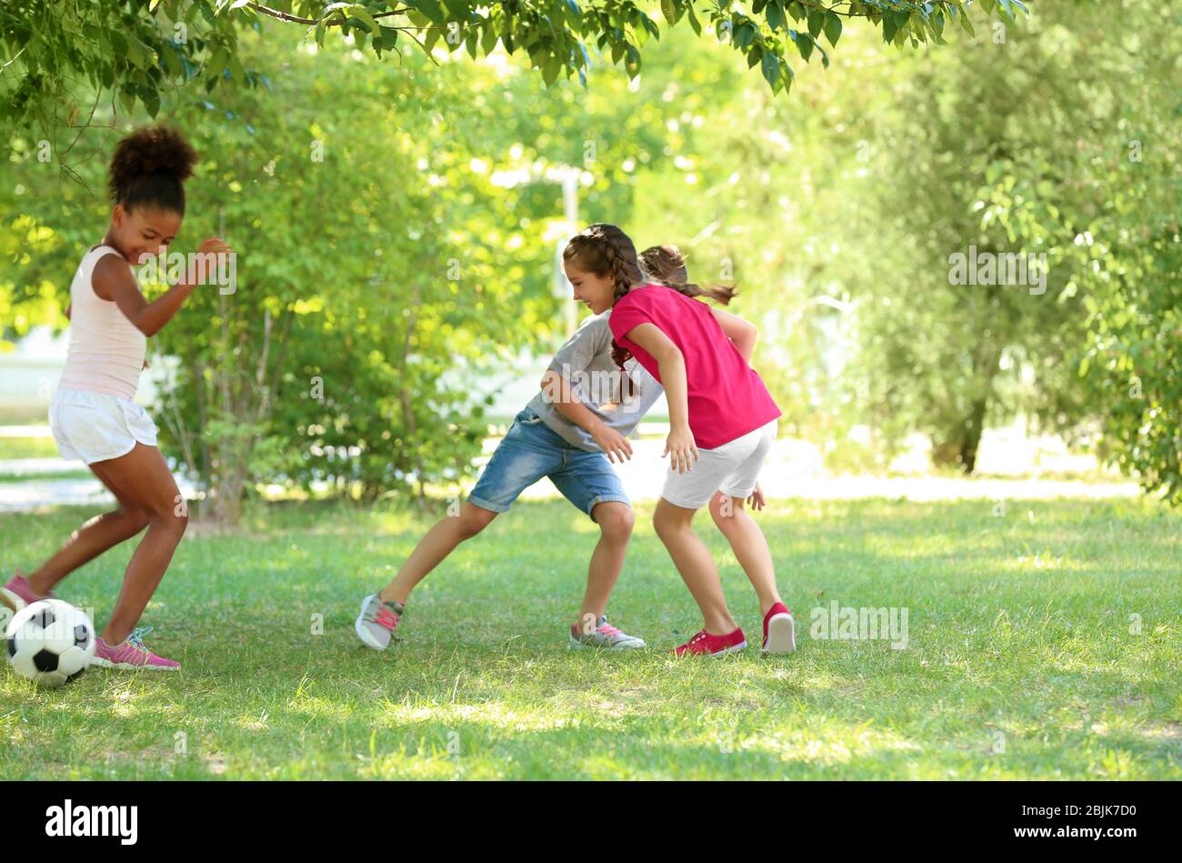 Cute children playing football in park Stock Photo - Alamy