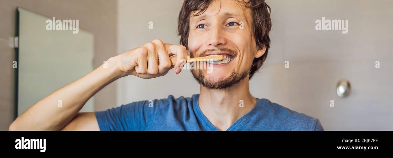 Personal hygiene concept. Pleased Caucasian young man carries bamboo toothbrush, satisfied to lead healthy lifestyle. Morning routine. Zero waste Stock Photo
