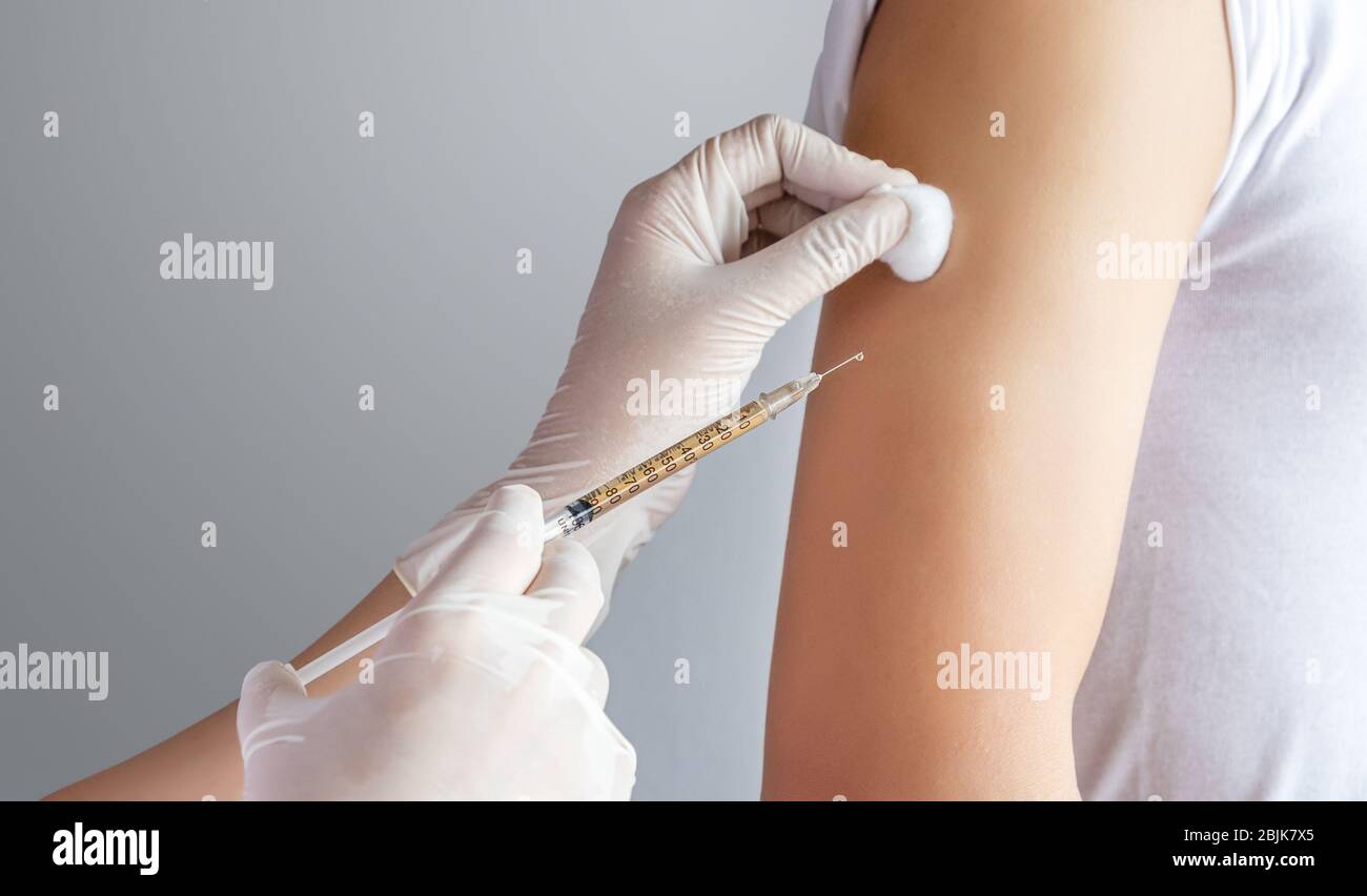 close-up of doctor, medical staff treating patient by injecting medicine in the upper arm at clinic or hospital. health care , treatment and vaccinati Stock Photo