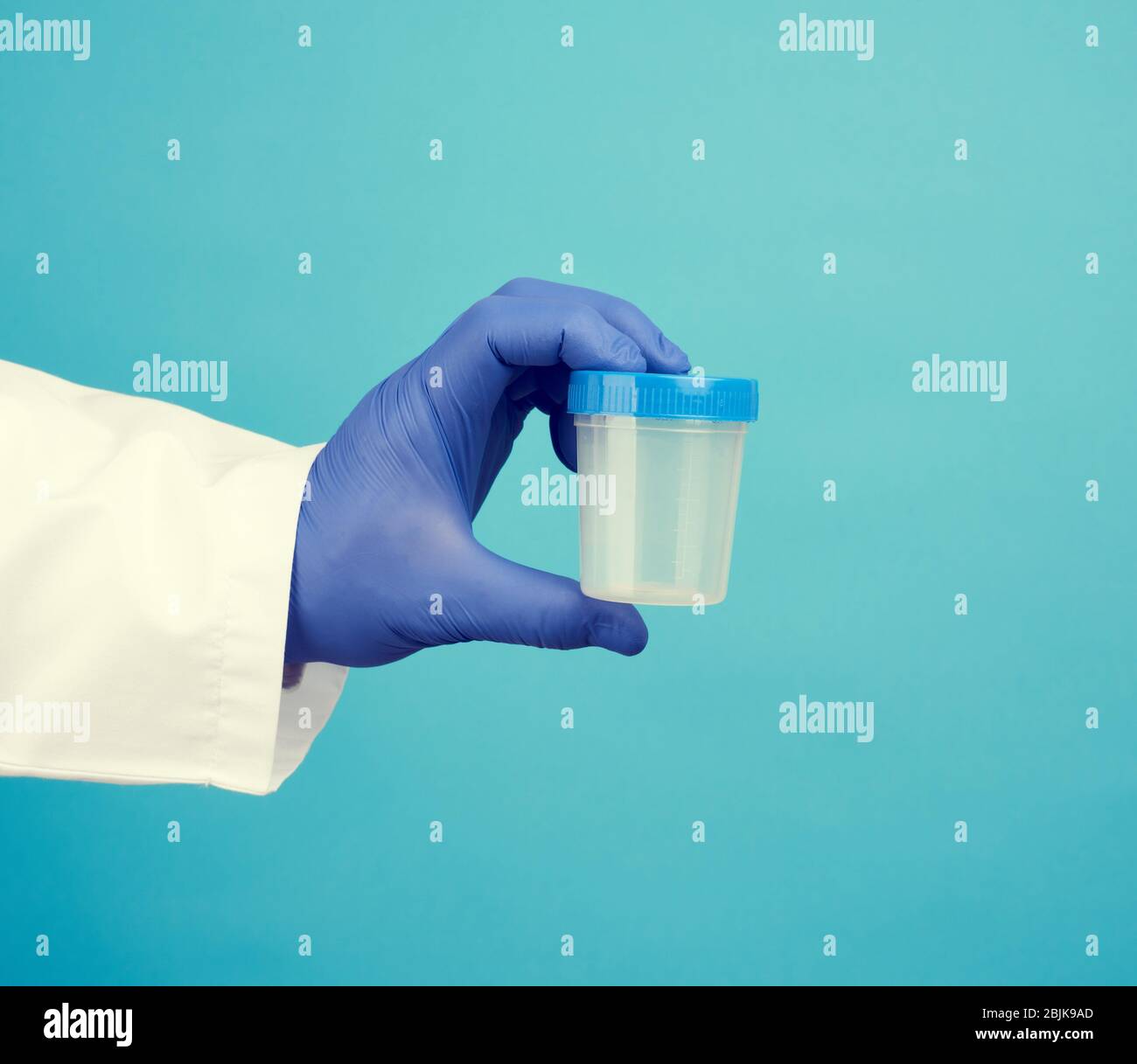 male doctor in a white coat holds a empty plastic container for urine
