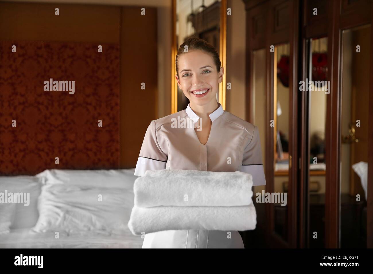 Chambermaid holding clean towels in hotel room Stock Photo Alamy