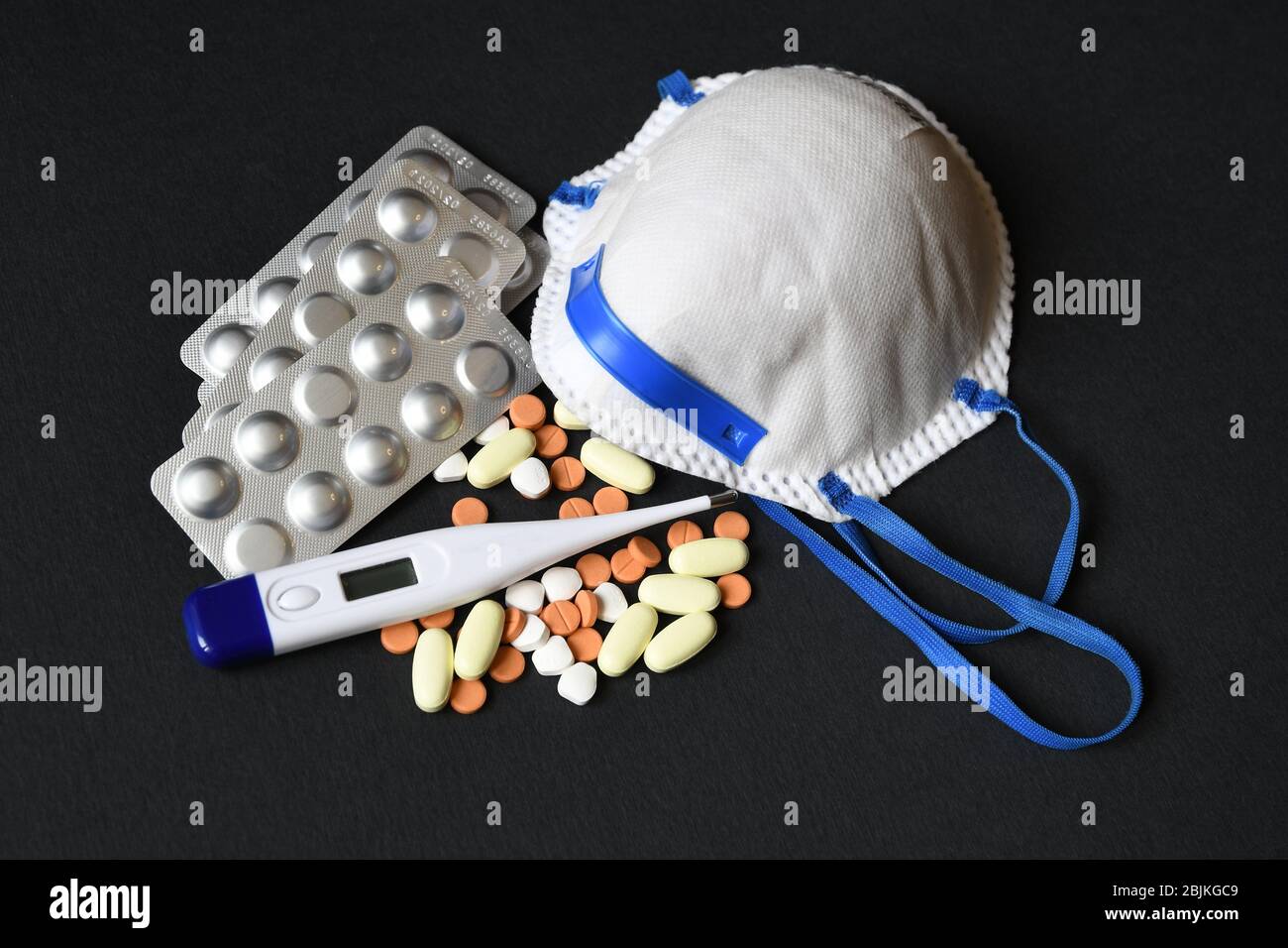 COVID-19 - Coronavirus disease - 2019-nCoV, concept of WUHAN corona virus. Protective mask together with medicine tablets and thermometer. Chinese Stock Photo