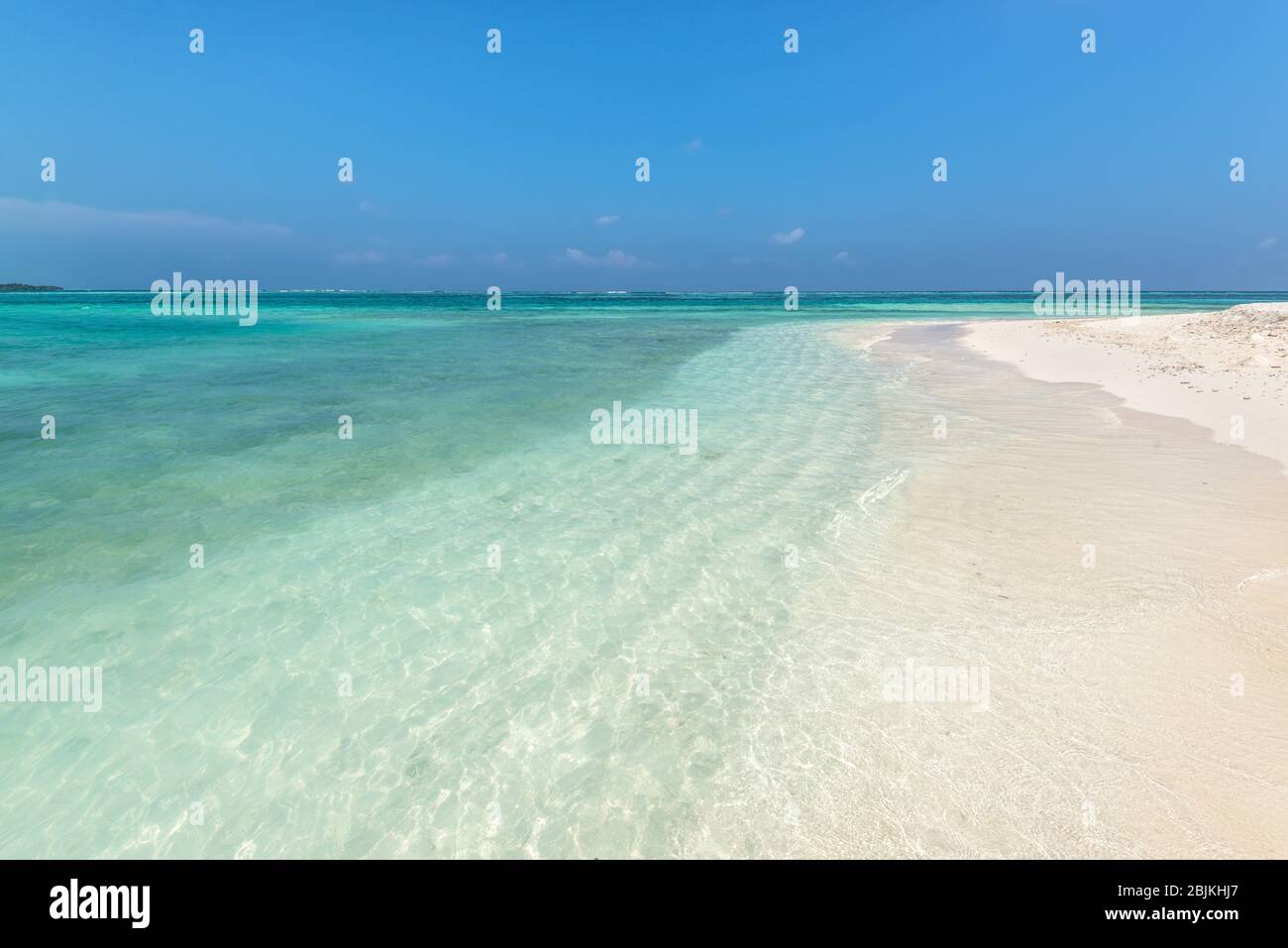 Amazing empty wild sandy beach with turquoise water. Picturesque seascape with blue sky. Maafushi Island, Maldives, Indian Ocean. Stock Photo