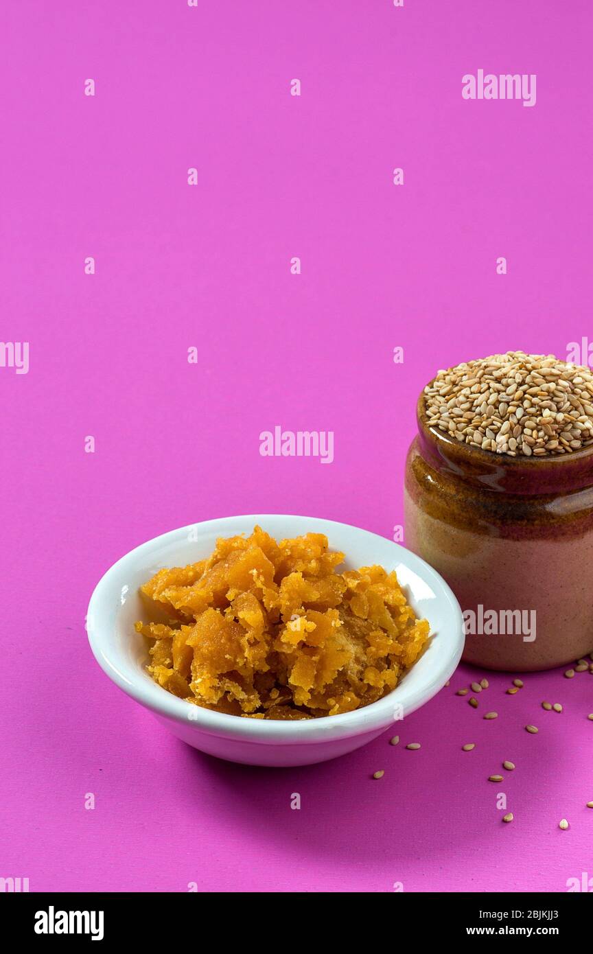 Sesame Seeds in clay pot with Jaggery in bowl on pink background Stock