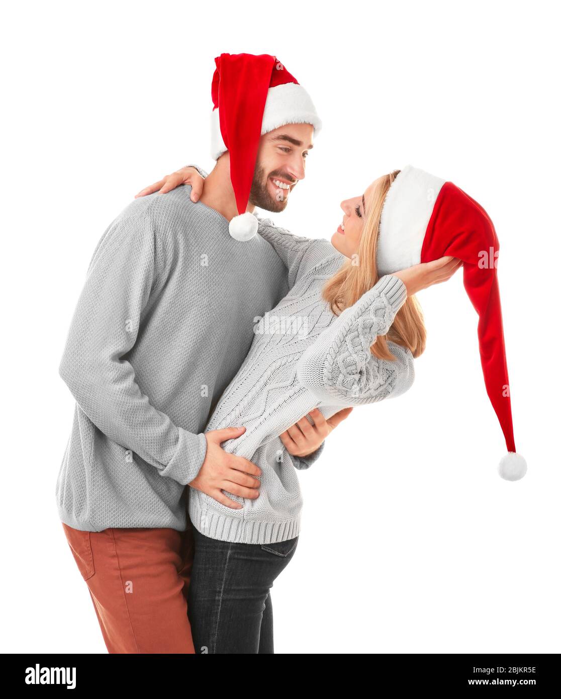 Happy young couple in Santa hats on white background. Christmas concept ...