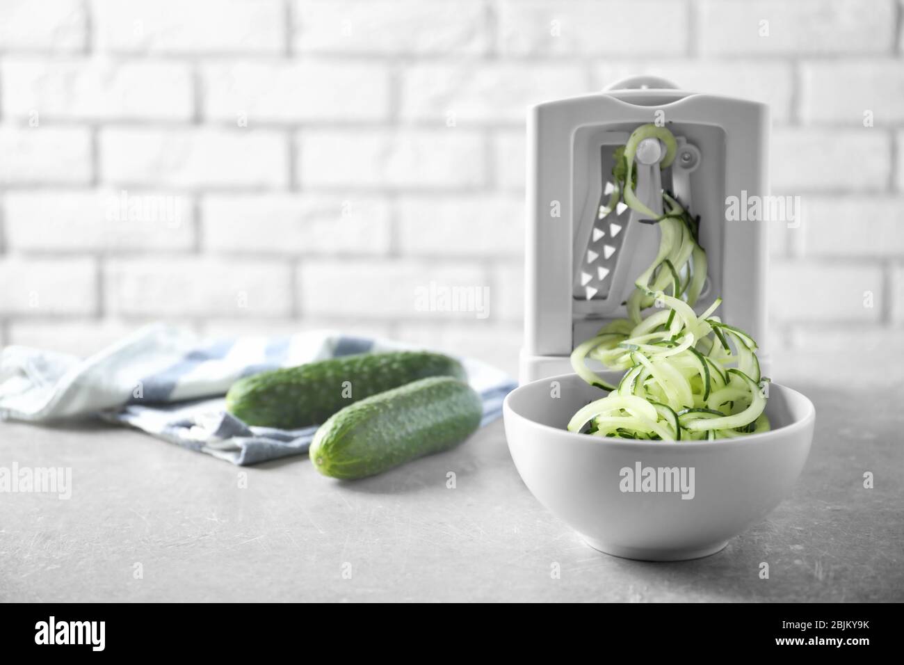 Spiral vegetable slicer with cucumber spaghetti on table Stock Photo