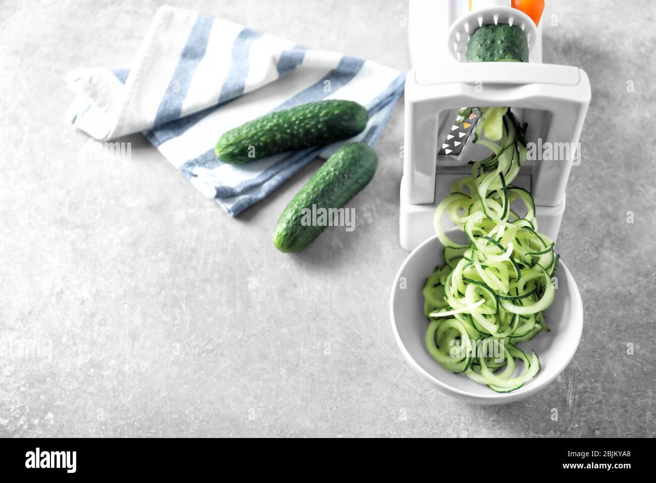 Spiral vegetable slicer with cucumber spaghetti on table Stock Photo