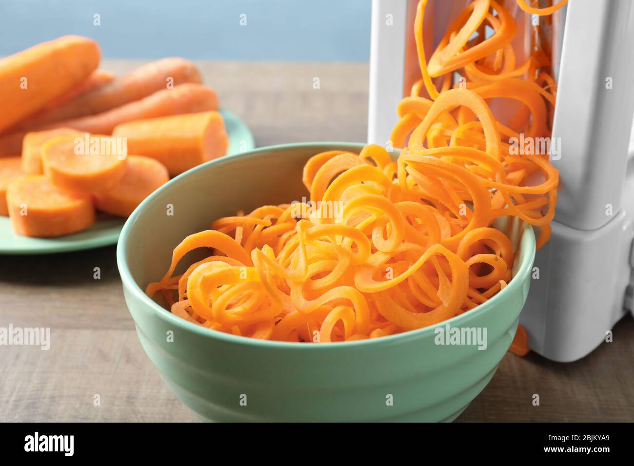 Spiral vegetable slicer with carrot spaghetti on table Stock Photo
