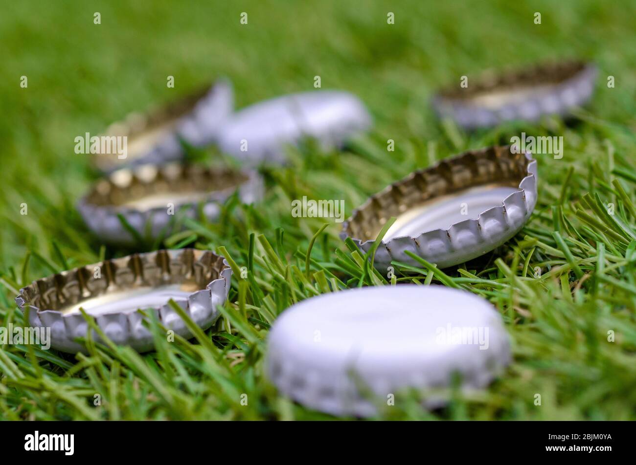 Pile of Discarded Beer Bottle Tops on Grass Stock Photo