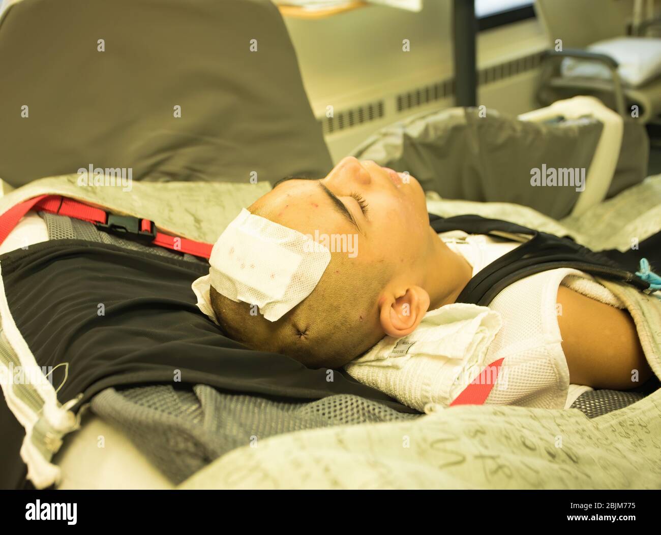 Young disabled teen boy lying in hospital bed unconscious after getting head or brain surgery Stock Photo