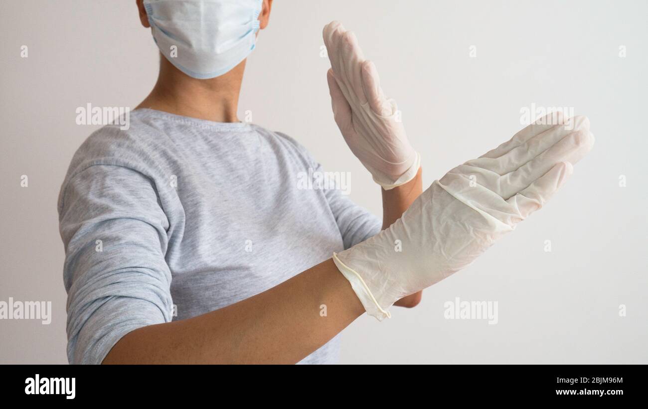 Woman with a white medical mask and latex glove in karate position. Stock Photo
