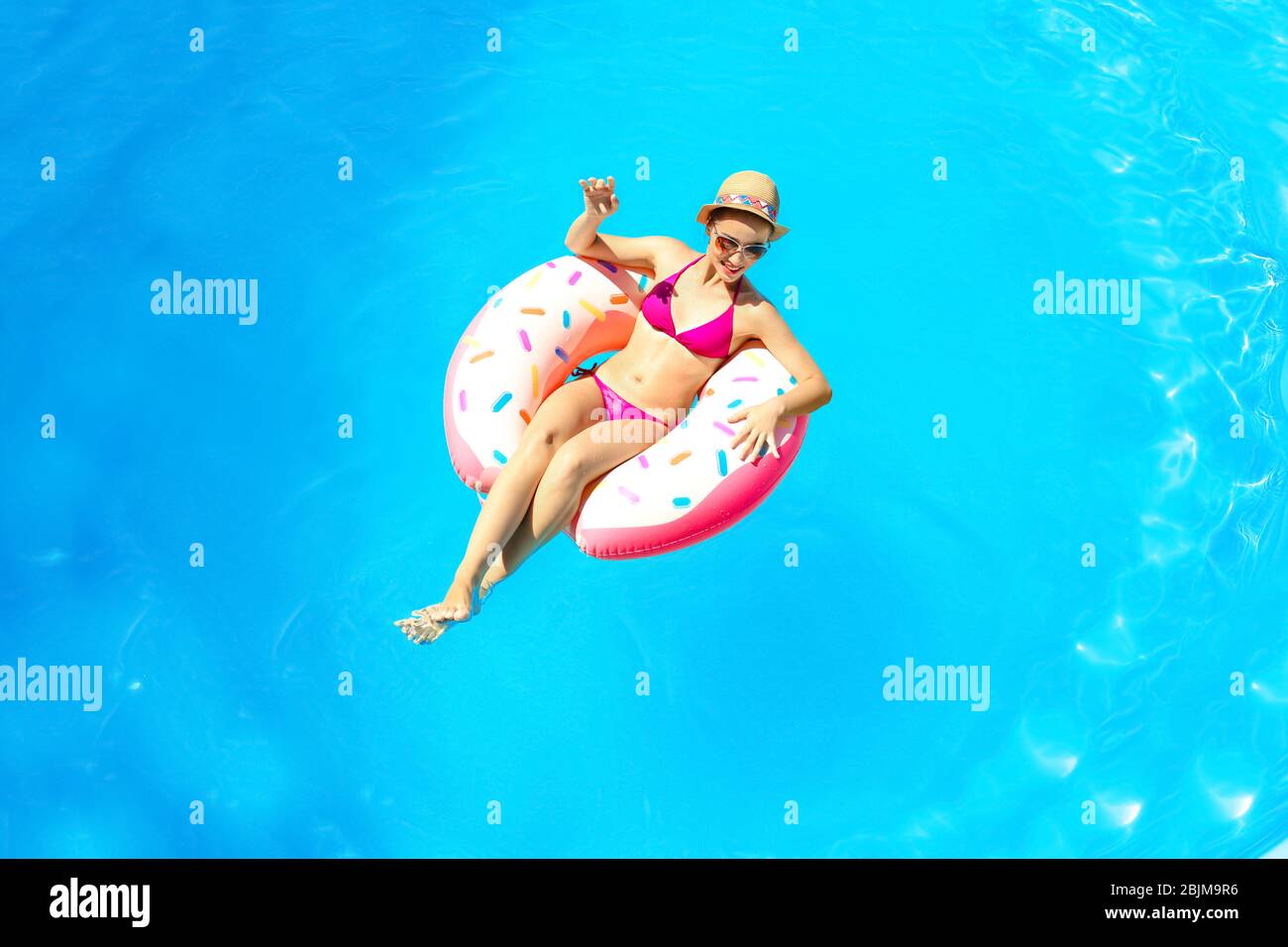 Young woman relaxing on inflatable donut in swimming pool Stock Photo