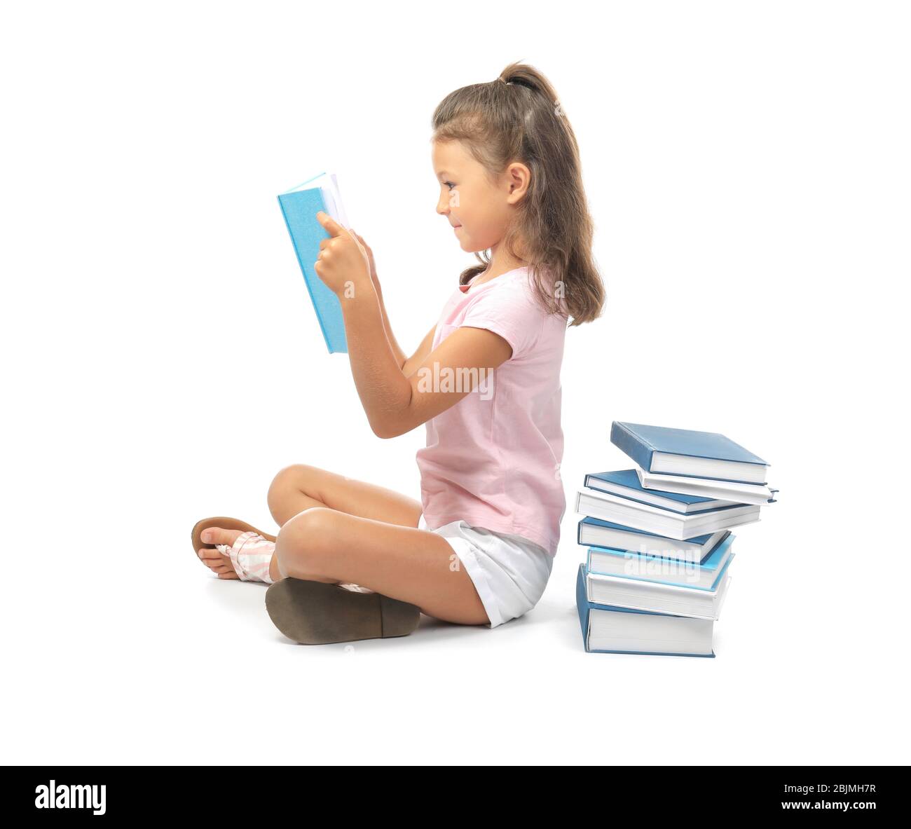 Cute little girl reading books on white background Stock Photo - Alamy