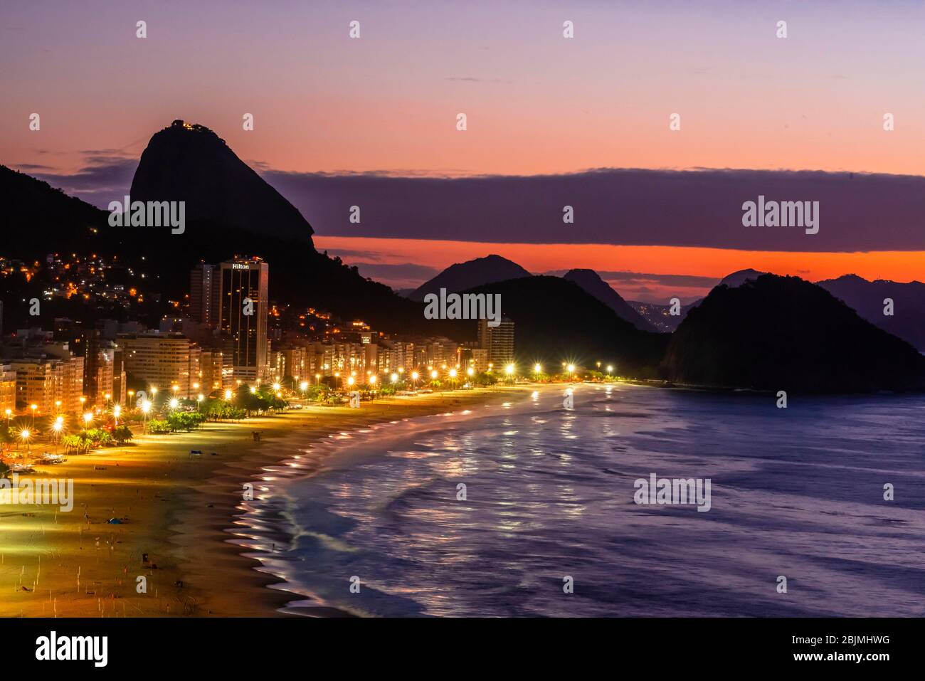 Overview of Avenida Atlantica and Copacabana Beach predawn, with Sugarloaf Mountain in background, Rio de Janeiro, Brazil. Stock Photo
