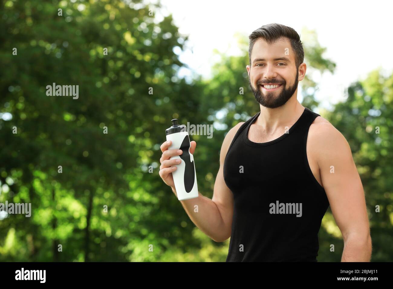 Sporty young man with bottle of water outdoors Stock Photo - Alamy