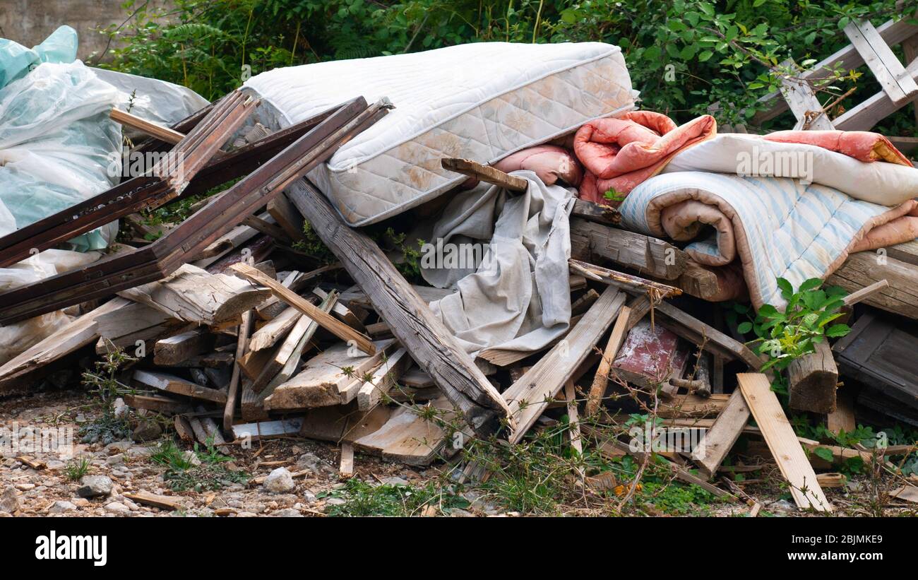 Garbage dumped boards, mattress, comforter, plastic bags full of