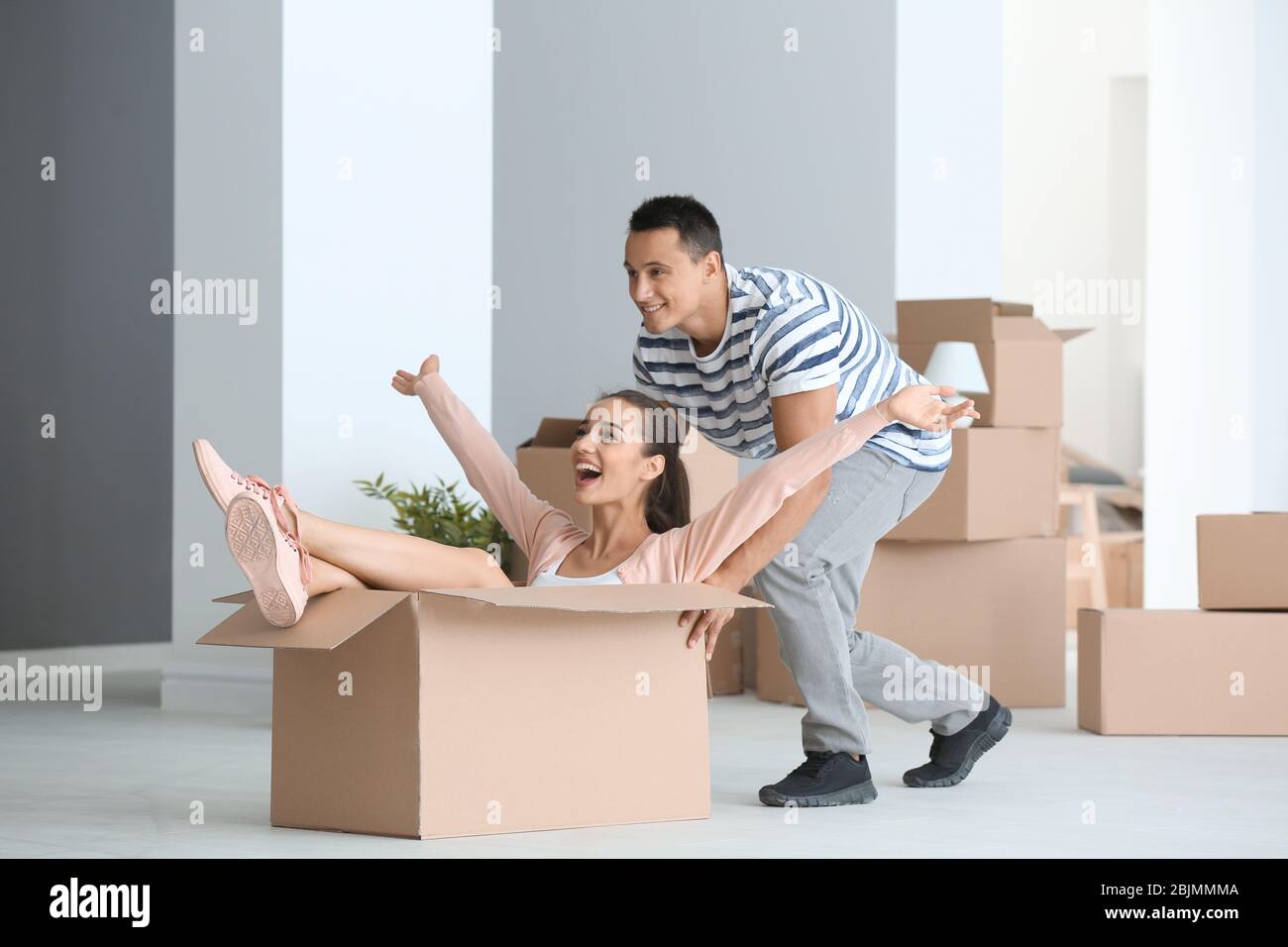 Happy young couple having fun while moving to new apartment Stock Photo ...
