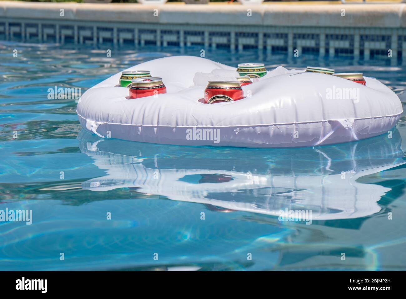Swimming pool with cans of beer in a floating drinks cooler Stock Photo