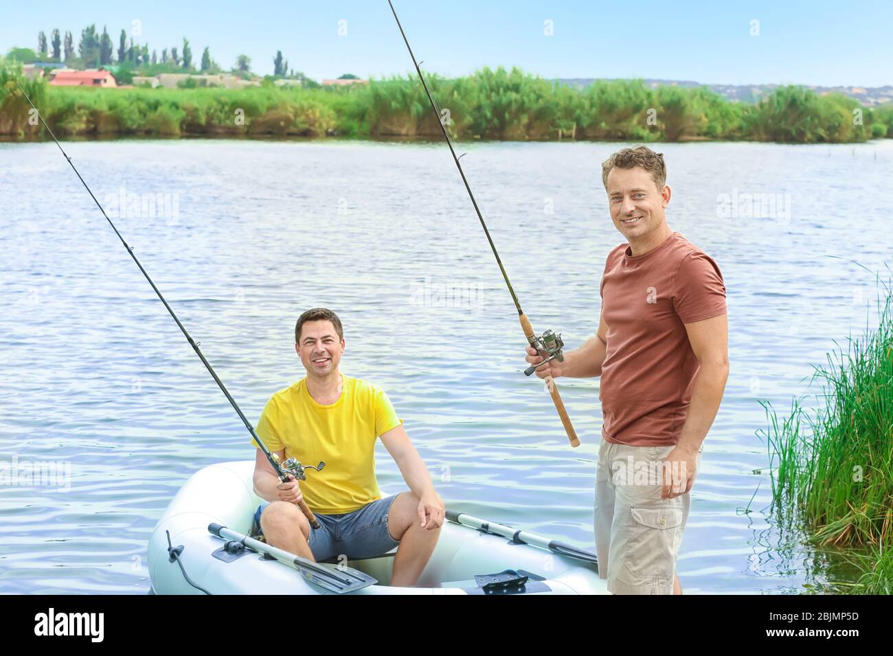 Two men fishing from inflatable boat on river Stock Photo - Alamy