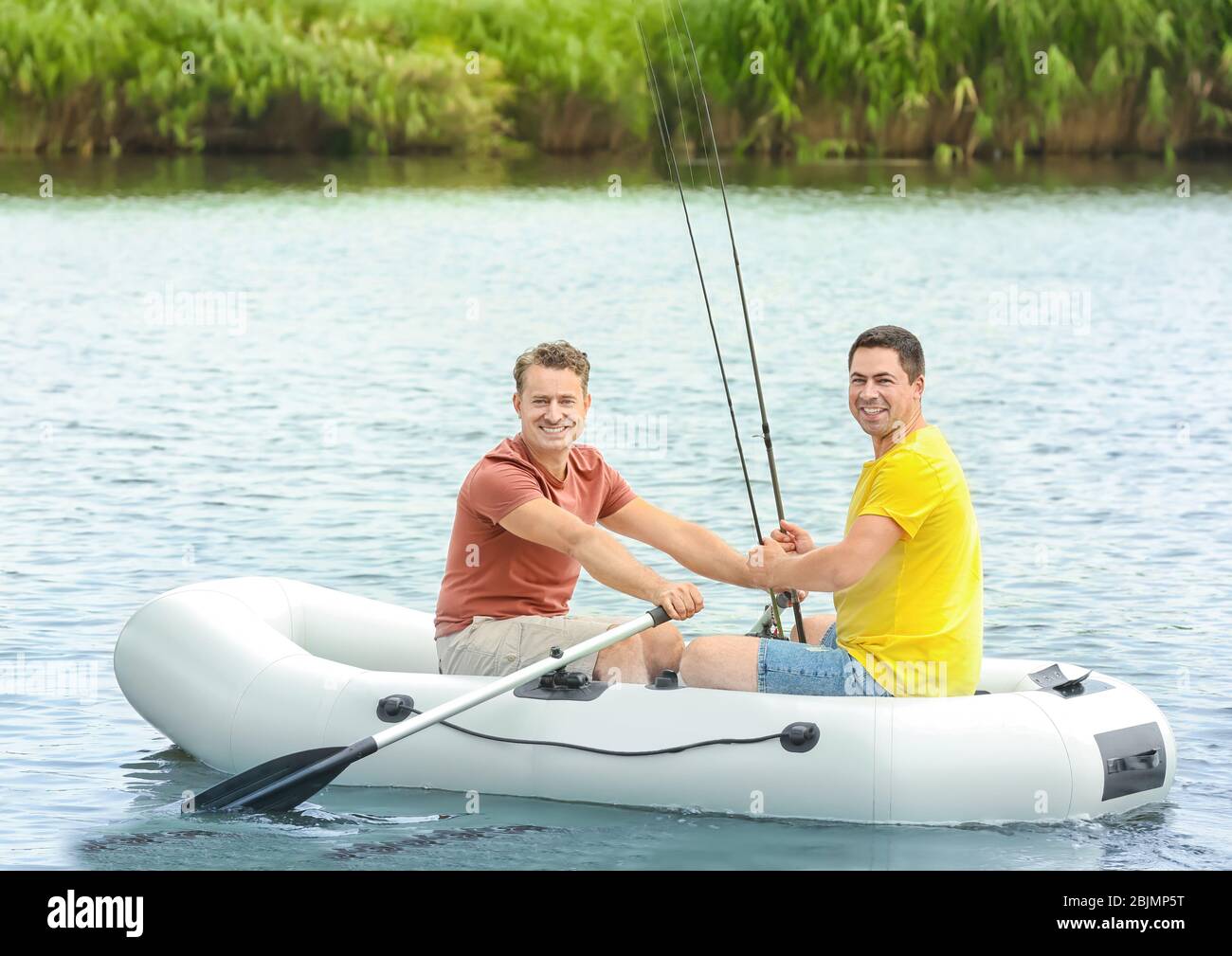 Two men fishing from inflatable boat on river Stock Photo - Alamy