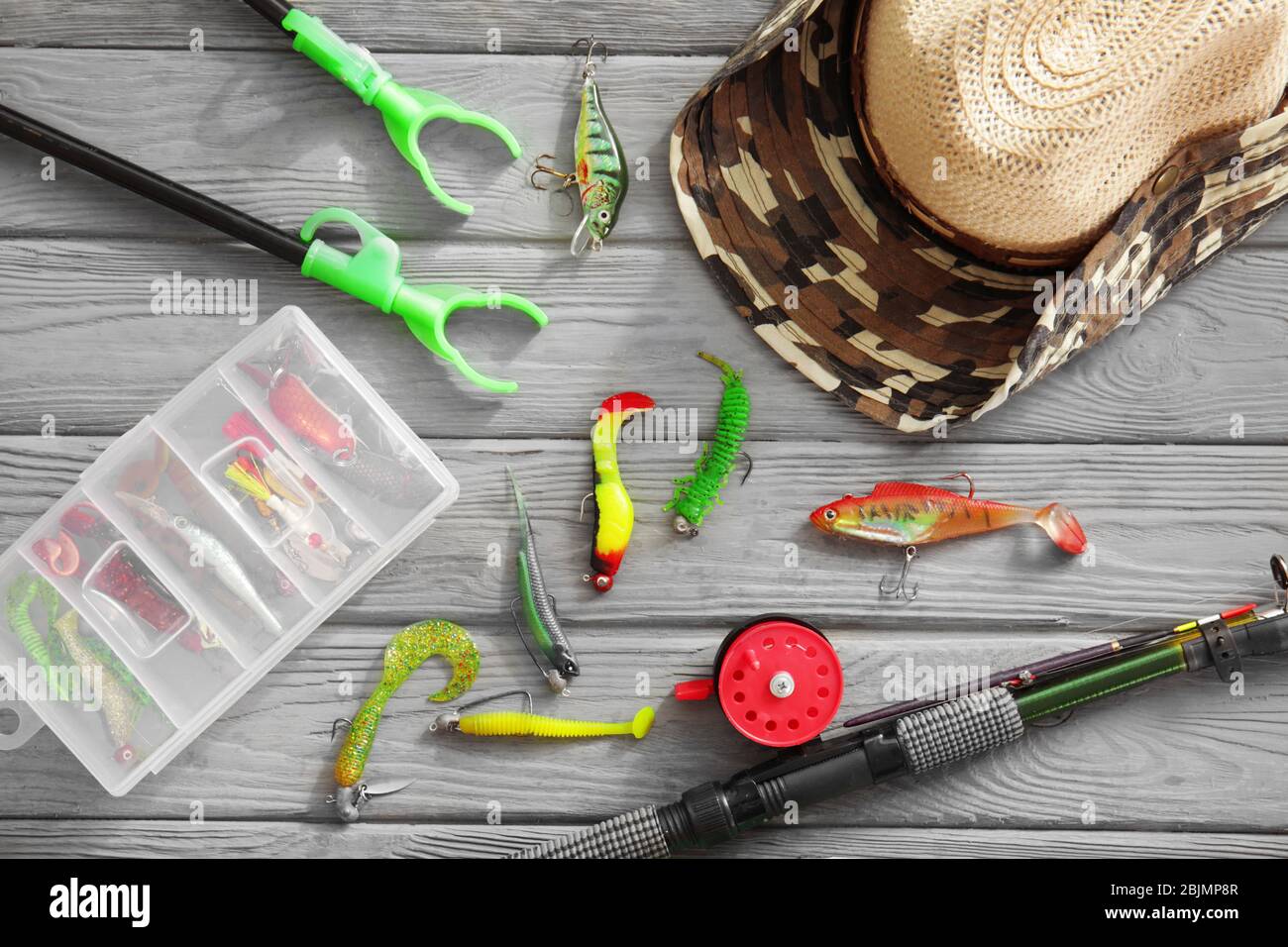 Flat lay of lure fishing tackle on a plain wooden background with