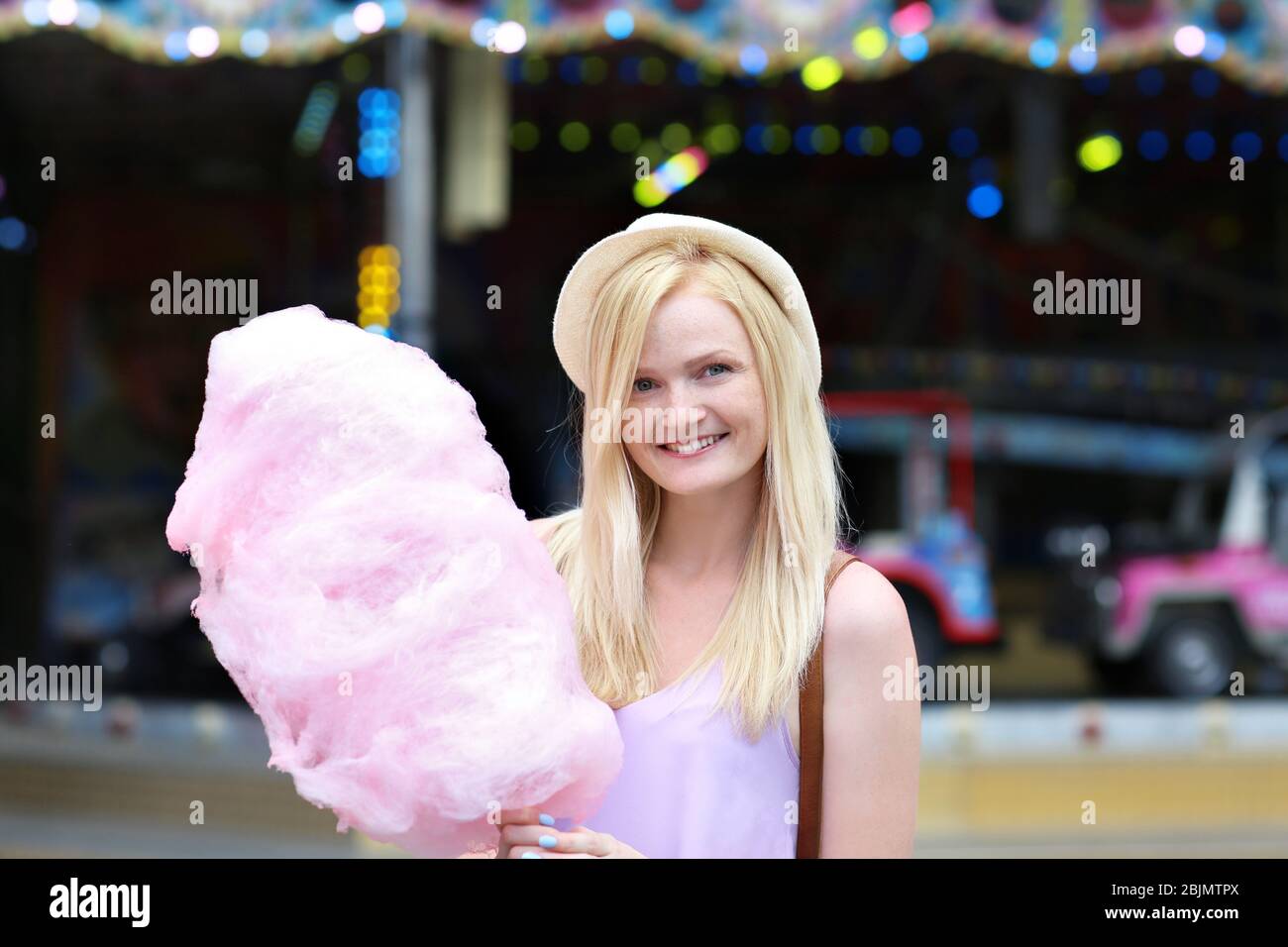 Young woman with cotton candy in amusement park Stock Photo - Alamy