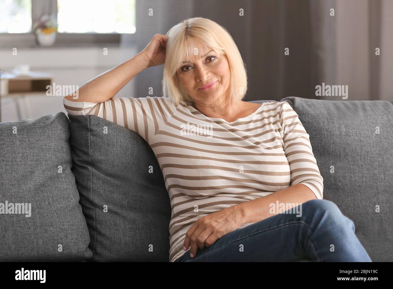 Mature woman sitting on couch hi-res stock photography and images - Alamy