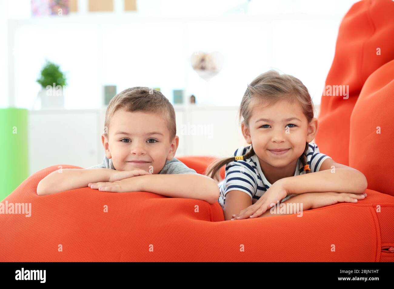 Cute boy and girl lying on bean bag cushion indoor Stock Photo - Alamy