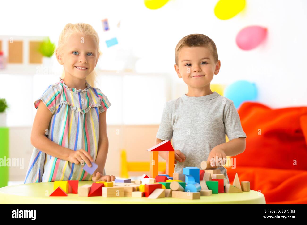 Cute children playing with blocks on table indoor Stock Photo - Alamy