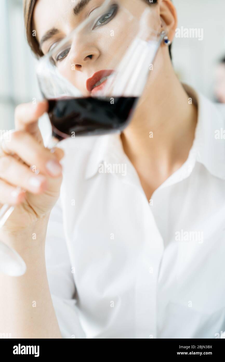 Portrait of a woman examining a glass of red wine Stock Photo - Alamy