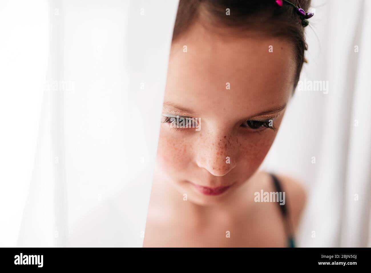 Portrait of a young girl wearing make-up standing by a curtain Stock Photo