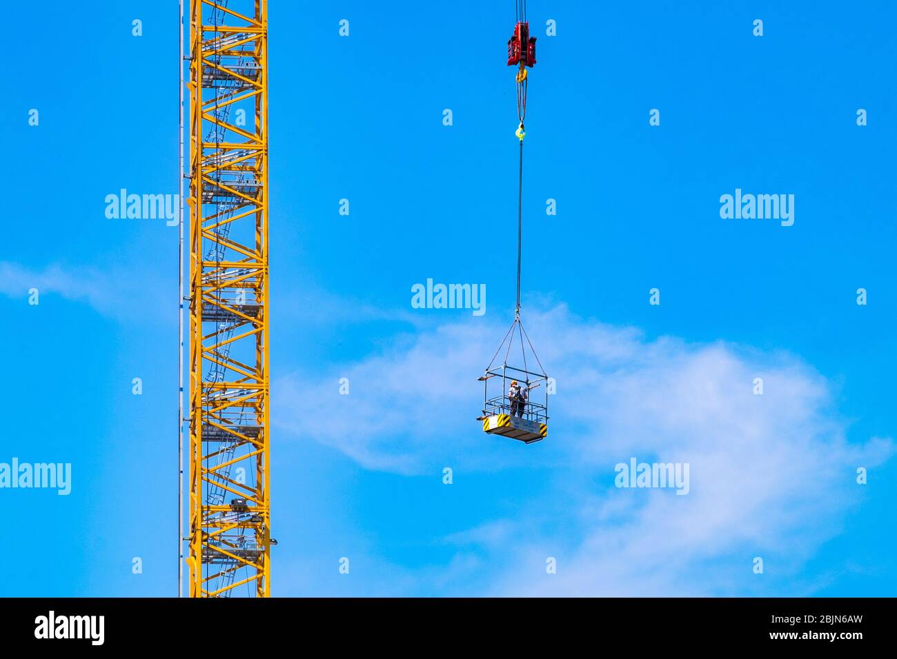 Construction worker hoisted up at a construction site at Strijp-S, Eindhoven, The Netherlands. Stock Photo