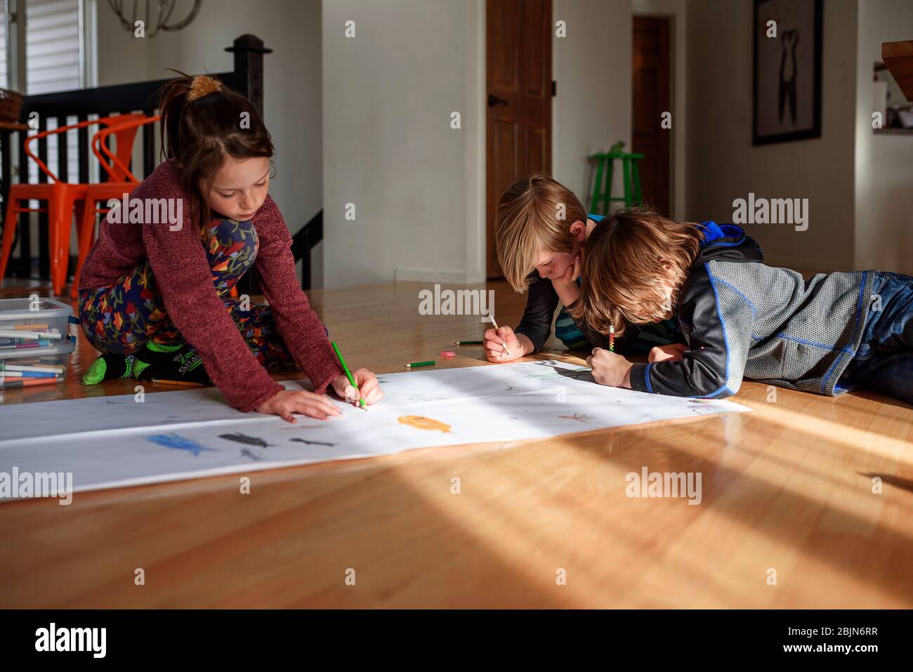 Three young children working on an art project at home Stock Photo