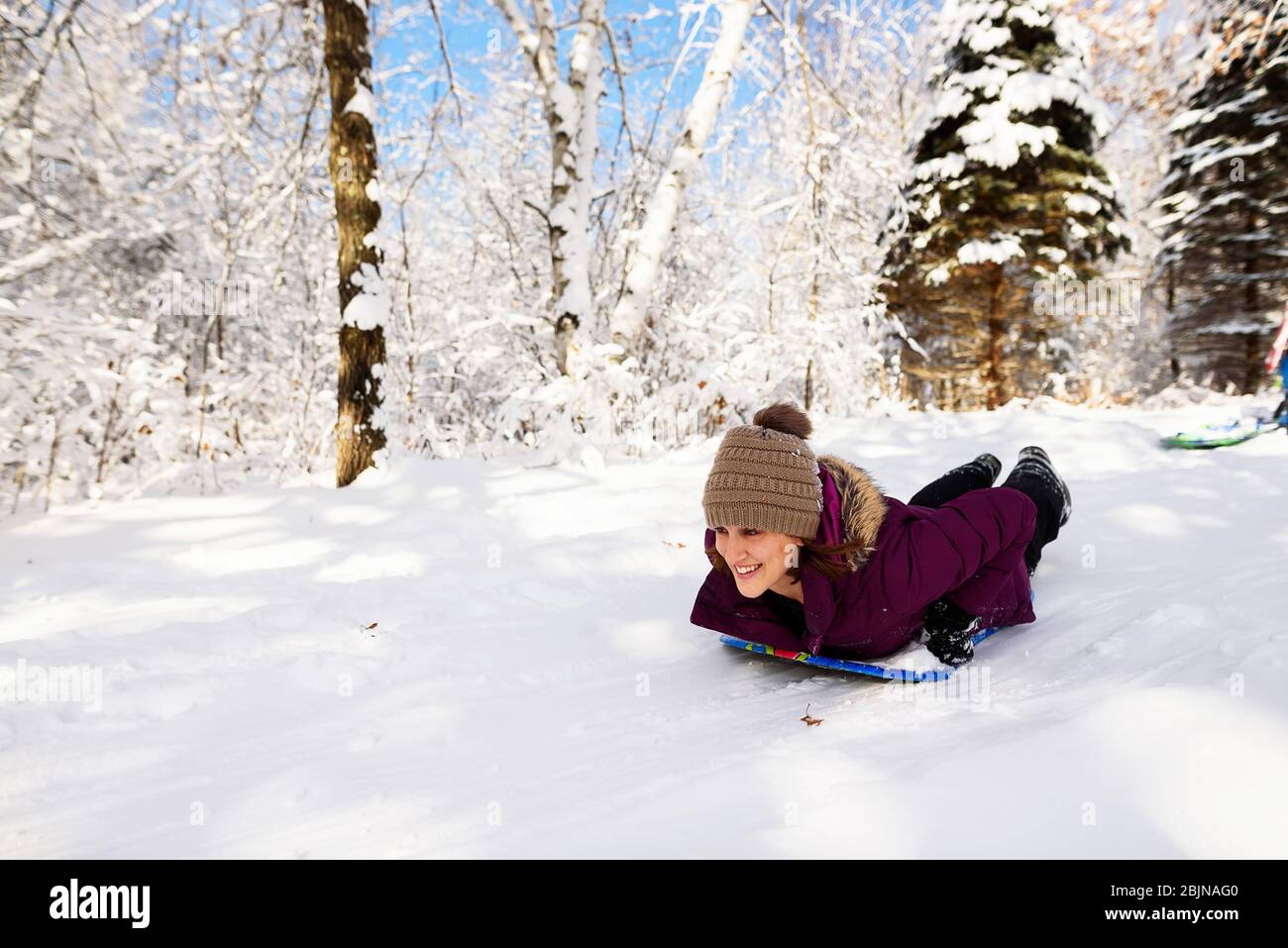 Woman sledding down a hill in the snow, USA Stock Photo