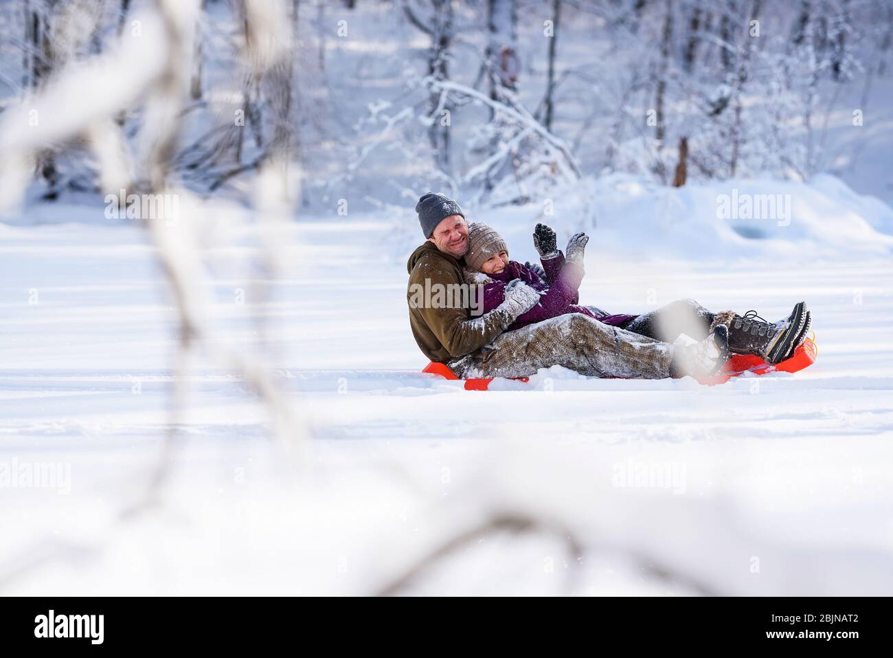 Man and woman sledding down a hill in the snow, USA Stock Photo