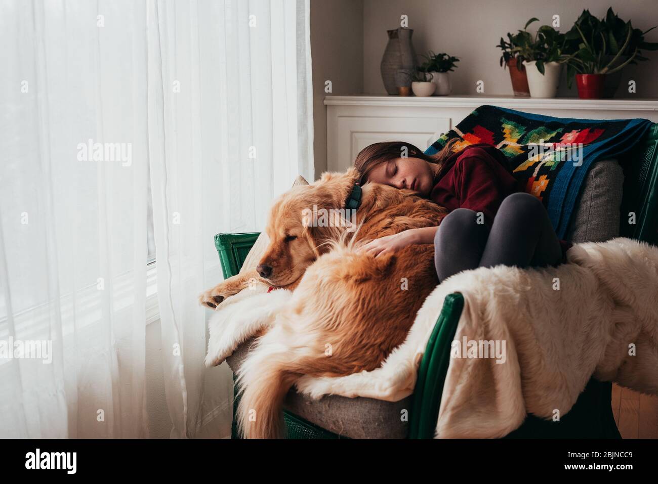 Girl sleeping on a sofa with her dog Stock Photo