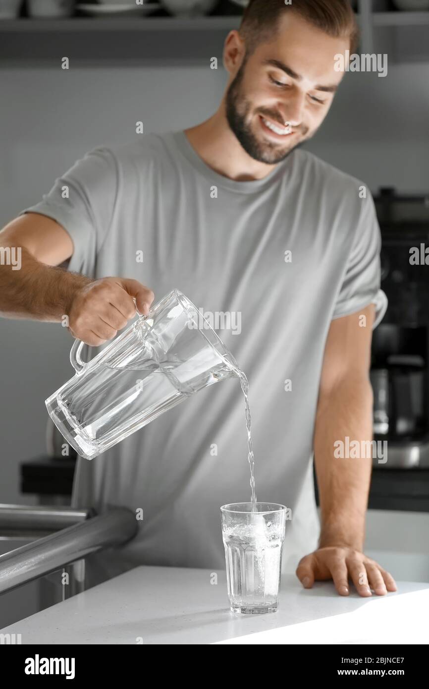 Morning of young man pouring water into glass in kitchen Stock Photo ...