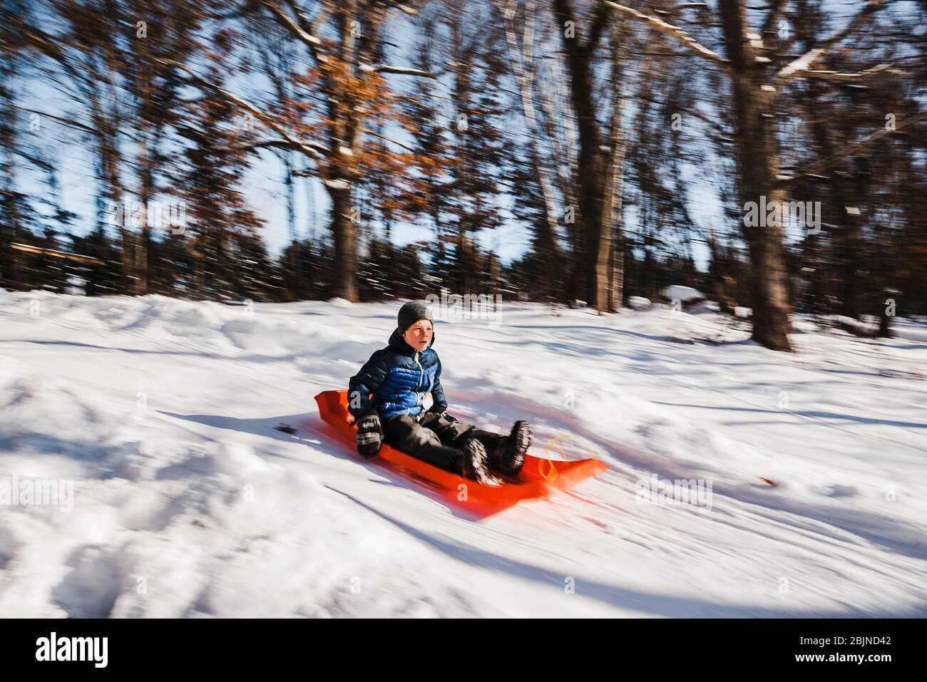 Boy sledding down a hill in the snow, USA Stock Photo