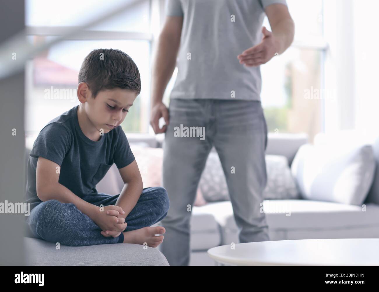 Little boy with bruises on face and man on background. Domestic violence concept Stock Photo