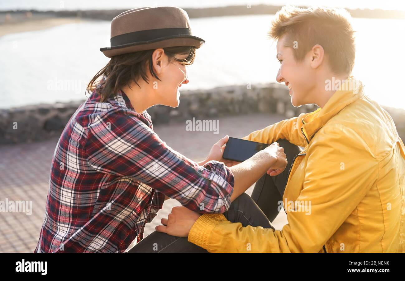 Happy gay couple using mobile smartphone outdoor - Young lesbians women having tender dating day moments together Stock Photo