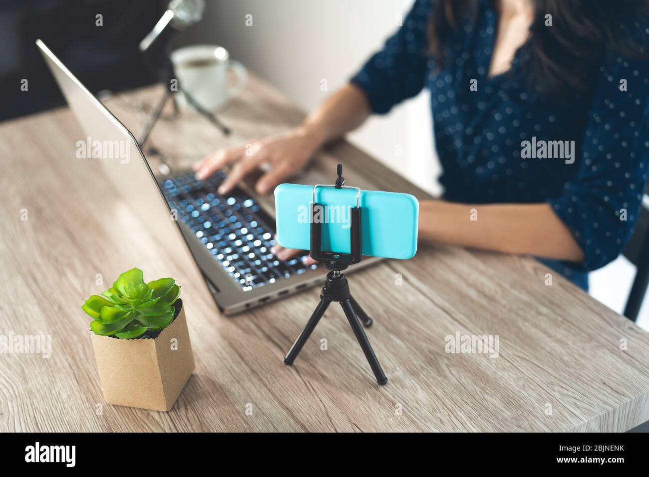 Happy female host filming video podcast with smart phone camera while using computer - Young girl having fun vlogging live streaming on social network Stock Photo