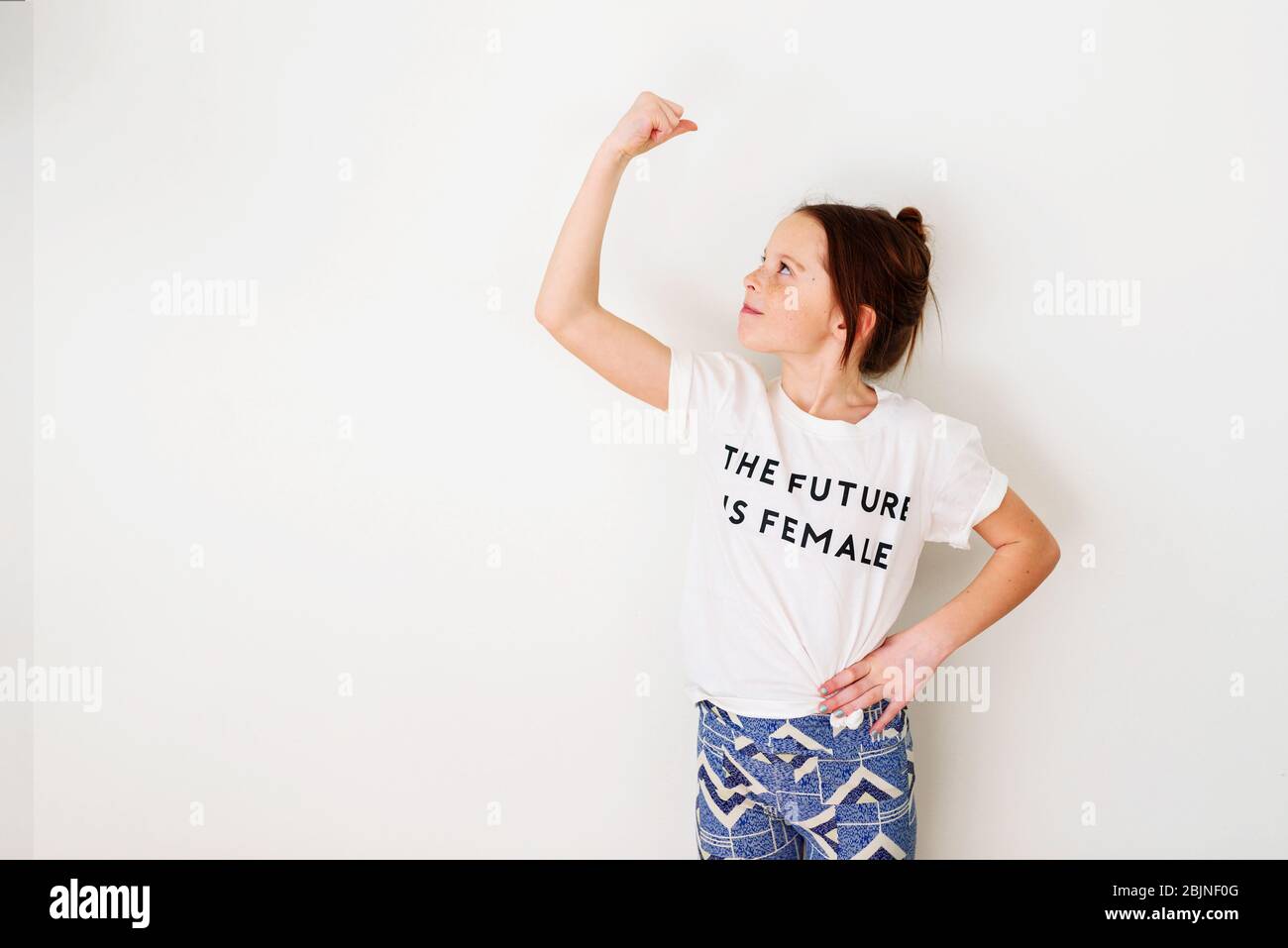 Girl standing by a wall flexing her muscles Stock Photo